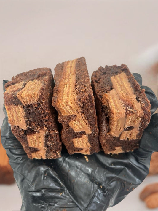 Three brownie slices held by a person wearing black gloves on a light background