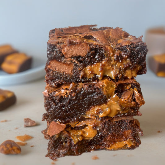 Stack of chocolate brownies with caramel bits on a light surface