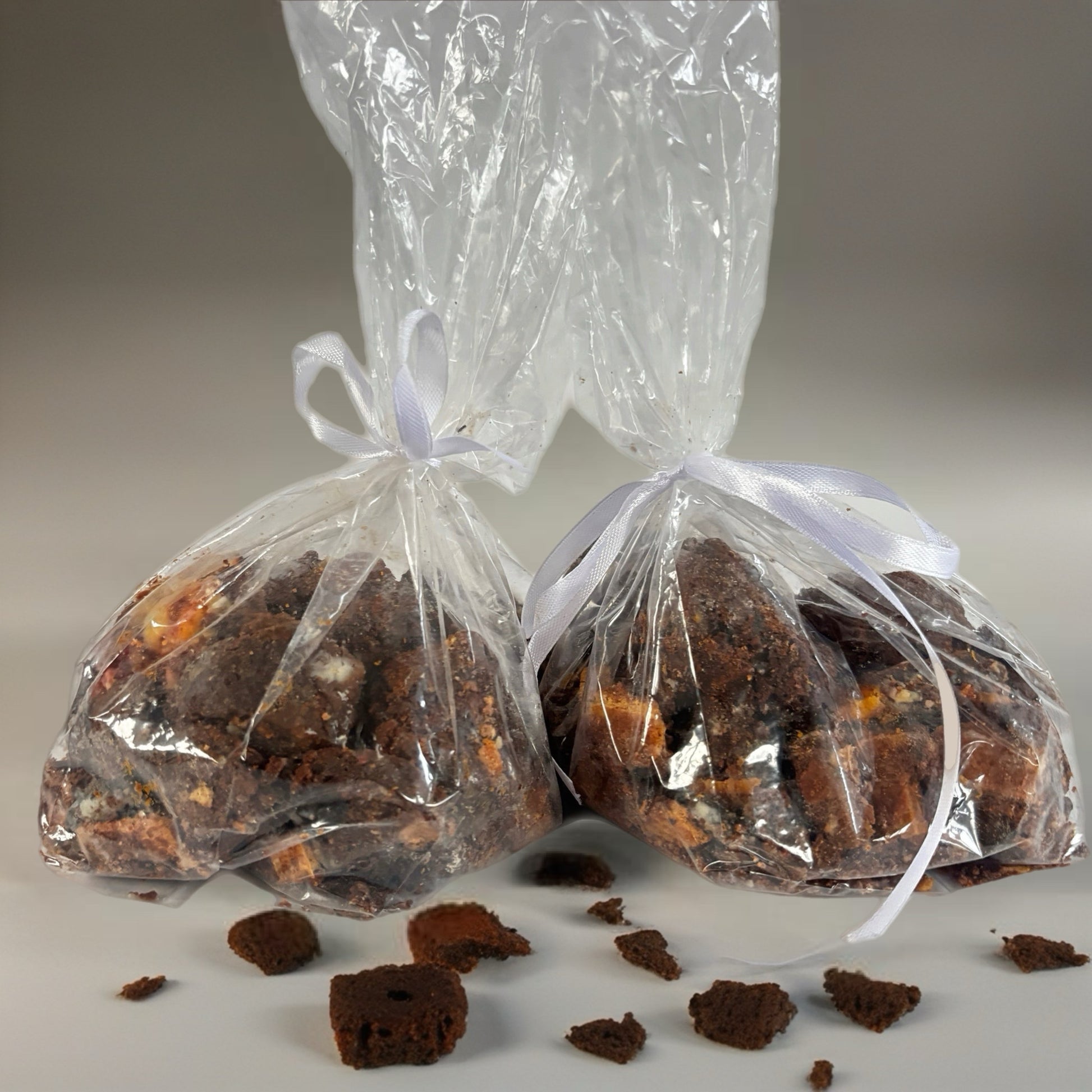 Two clear plastic bags with white ribbons containing brownies on a gray background