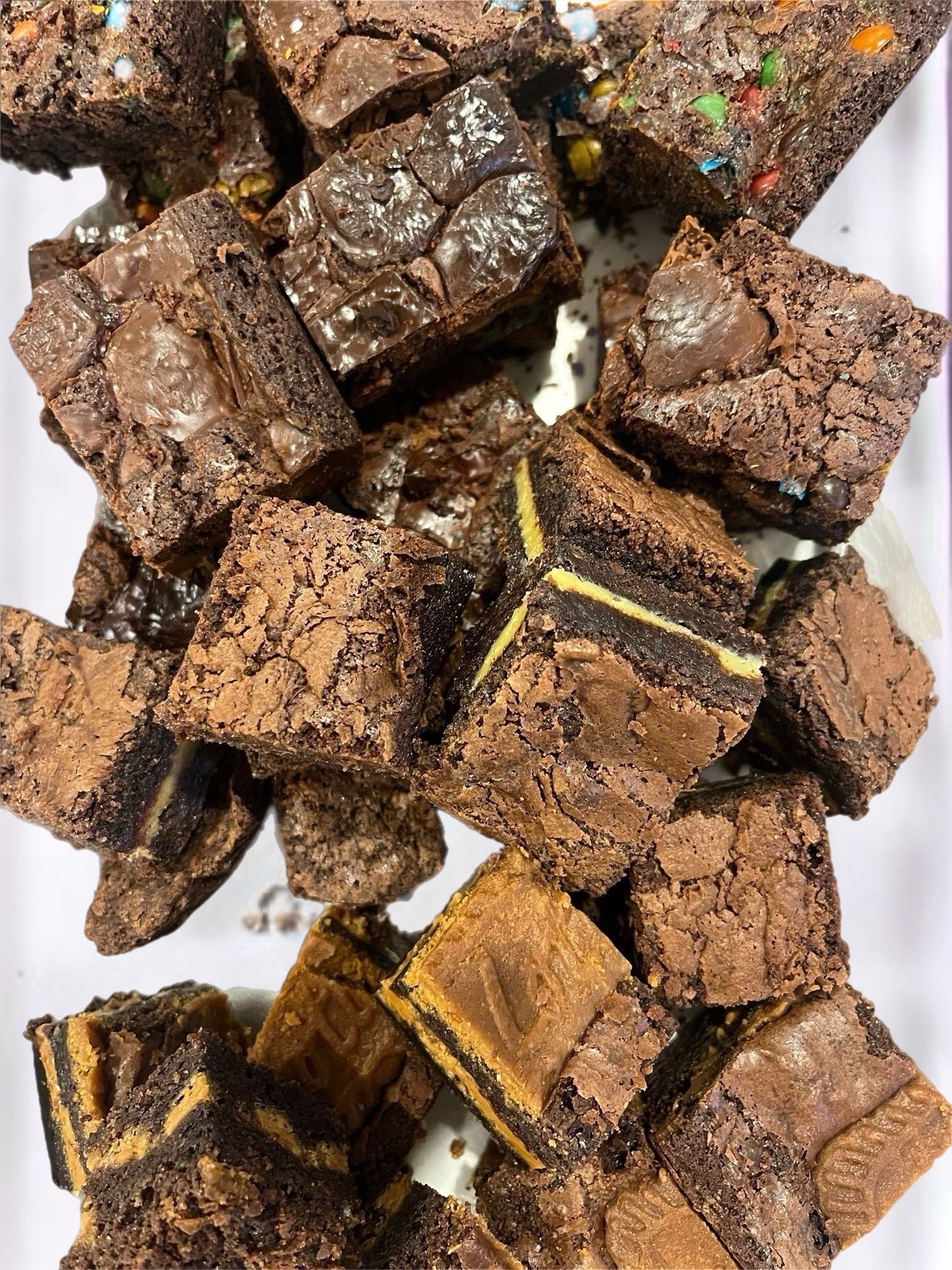 Pile of brownies with visible chocolate and candy pieces on a white background