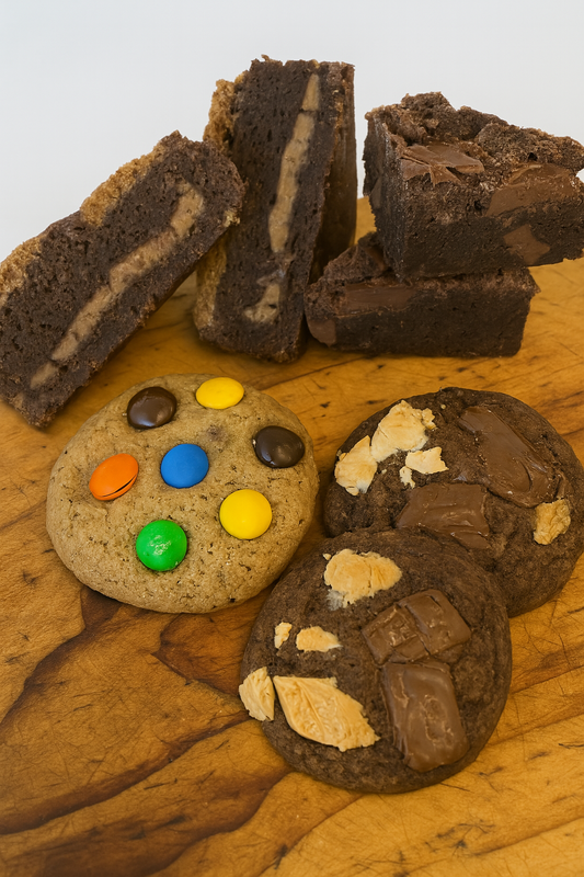 Assorted chocolate cookies and brownies on a wooden surface