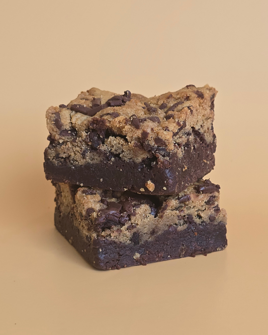Stack of two brookie desserts, which are a blend of brownie and cookie, with visible chocolate chips, on a plain background.
