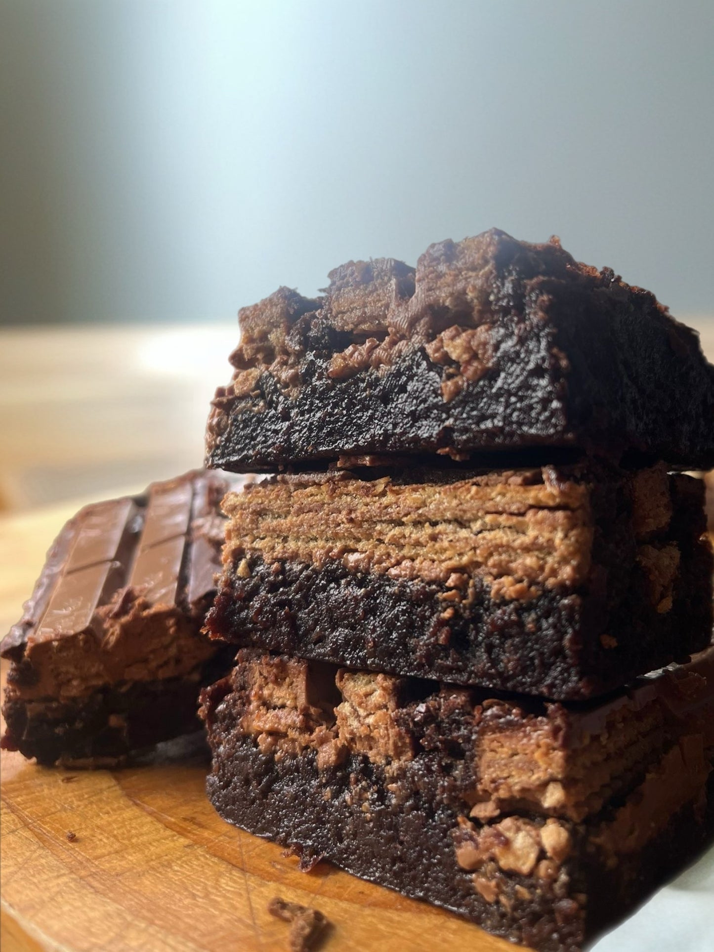 Stack of brownies on a wooden surface with a blurred background