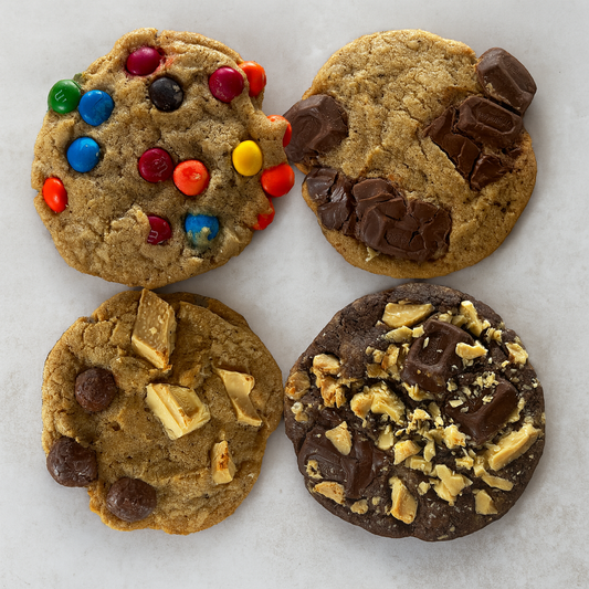 Four different types of cookies with various toppings on a white surface